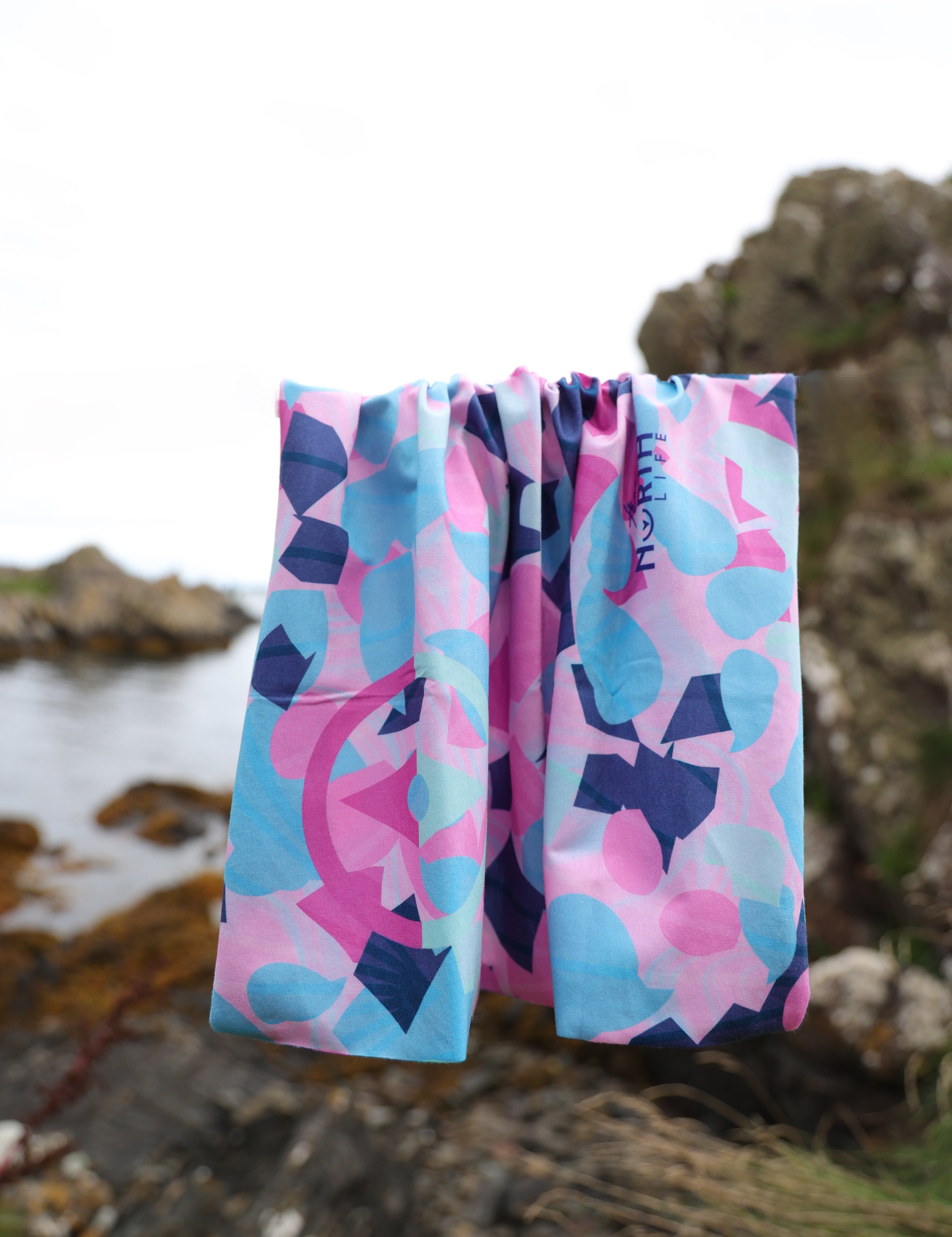 Cerise, soft pink, turquoise, mint and navy Infinity Band or snood hanging before rocks outdoors displaying the colours and terrazzo pattern.